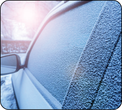 Window of the car covered with frost during winter morning and sun flare light reflecting